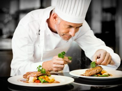 Concentrated male chef garnishing food in kitchen