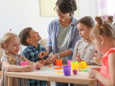 Young woman playing with little children indoors