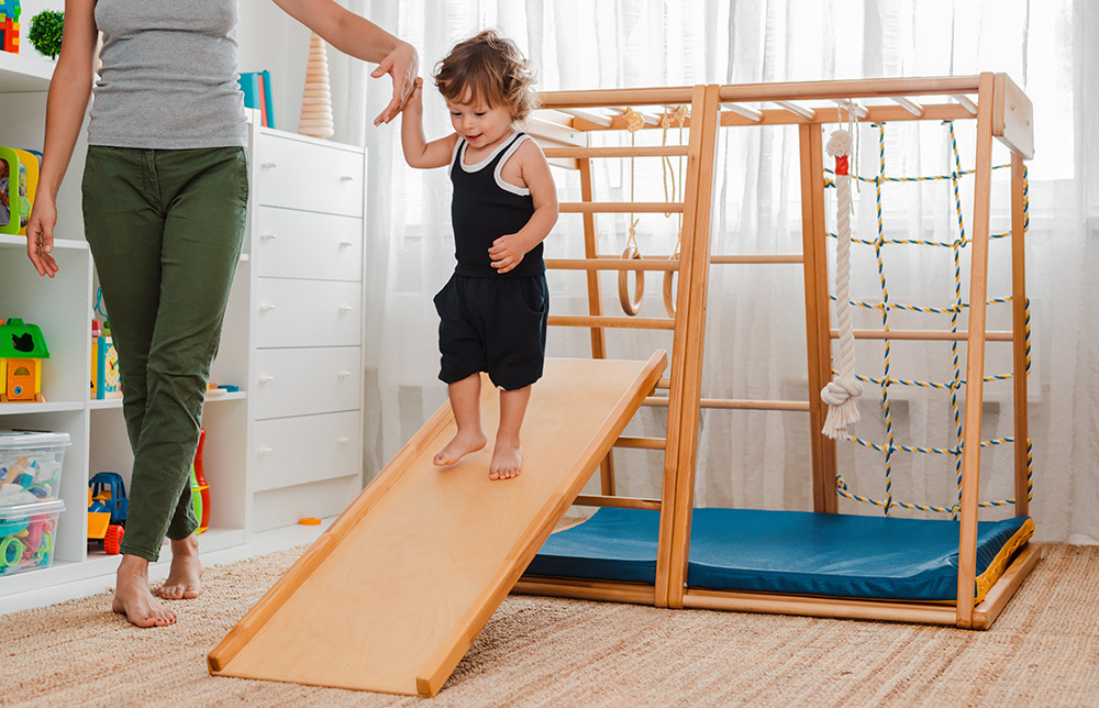child at an early age of 1.5 years is engaged in the home children's wooden sports complex.